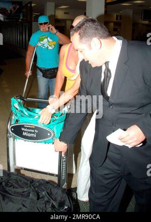 Exclusive!! Terry Bollea (aka Hulk Hogan) and girlfriend Jennifer McDaniel arrive at Miami International Airport after a flight from Tampa. The two strolled slowly through the terminal as Hulk walked carefully, using crutches because of recent back surgery. Jennifer pushed their luggage cart and helped him navigate the bottom of an escalator before the two met the driver of their waiting car who took care of their luggage. Hogan was involved in a heated courtroom argument yesterday in Tampa with ex-wife Linda Bollea's attorney after a hearing in which Hulk asked a judge to allow him access to Stock Photo