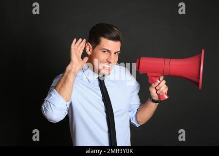Handsome man with megaphone on black background Stock Photo