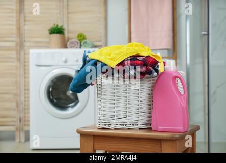 Wicker basket with laundry and detergent in bathroom Stock Photo