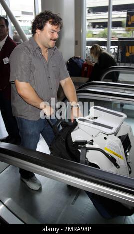 EXCLUSIVE!! Actor and funnyman Jack Black carries along an infant's car seat as he arrives for a flight at LAX. Black, who made faces for photographers as he ascended an elevator, is set to star alongside Matthew McConaughey, Shirley MacLaine and Rip Torn in the new black comedy 'Bernie.' The movie is based on a true story and tells the tale of a small-town funeral home director in Texas. Los Angeles, CA. 10/3/10. Stock Photo