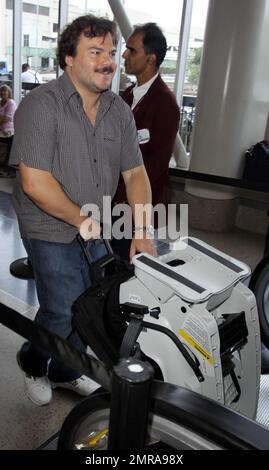 EXCLUSIVE!! Actor and funnyman Jack Black carries along an infant's car seat as he arrives for a flight at LAX. Black, who made faces for photographers as he ascended an elevator, is set to star alongside Matthew McConaughey, Shirley MacLaine and Rip Torn in the new black comedy 'Bernie.' The movie is based on a true story and tells the tale of a small-town funeral home director in Texas. Los Angeles, CA. 10/3/10. Stock Photo