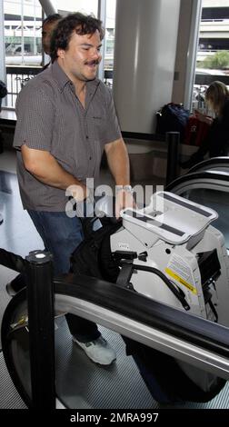 EXCLUSIVE!! Actor and funnyman Jack Black carries along an infant's car seat as he arrives for a flight at LAX. Black, who made faces for photographers as he ascended an elevator, is set to star alongside Matthew McConaughey, Shirley MacLaine and Rip Torn in the new black comedy 'Bernie.' The movie is based on a true story and tells the tale of a small-town funeral home director in Texas. Los Angeles, CA. 10/3/10. Stock Photo