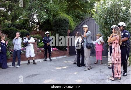 Fans and friends gather outside the Jackson family compound to leave flowers and gifts and pay their respects as the family arrives from UCLA Medical Center where Michael Jackson was pronounced dead after suffering from cardiac arrest this afternoon. Encino, CA. 6/25/09. . Stock Photo