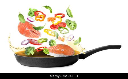 Many different ingredients falling into frying pan on white background. Delicious recipe Stock Photo
