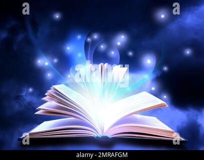Open book with fairytales and magic lights on blue background. Creative design Stock Photo