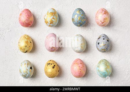 Decorated multicolor pastel Easter eggs with gold on white table. Flat lay geometric pattern. Happy Easter card. Stock Photo