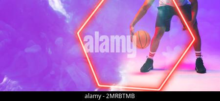 Low section of biracial basketball player dribbling ball by hexagon over smoky background Stock Photo