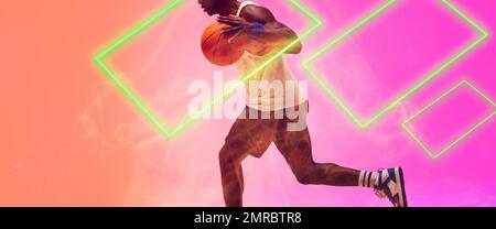 Low section of african american basketball player running and dribbling ball by rectangles Stock Photo