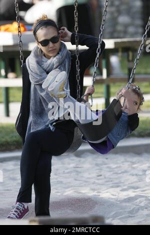 Pregnant Jessica Alba shows off her growing baby bump in a loose fitting grey top as she plays at the park with her daughter Honor Marie, who looked very happy in a trendy denim vest as she held mom's hand to jump down some steps.  Later Alba, who also wore comfy purple sneakers, a swathing grey scarf and held her hair back with a hairband, stayed close by as Honor had a go at the swings. Los Angeles, CA. 03/13/11. Stock Photo