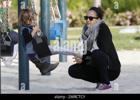 Pregnant Jessica Alba shows off her growing baby bump in a loose fitting grey top as she plays at the park with her daughter Honor Marie, who looked very happy in a trendy denim vest as she held mom's hand to jump down some steps.  Later Alba, who also wore comfy purple sneakers, a swathing grey scarf and held her hair back with a hairband, stayed close by as Honor had a go at the swings. Los Angeles, CA. 03/13/11. Stock Photo