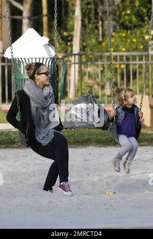 Pregnant Jessica Alba shows off her growing baby bump in a loose fitting grey top as she plays at the park with her daughter Honor Marie, who looked very happy in a trendy denim vest as she held mom's hand to jump down some steps.  Later Alba, who also wore comfy purple sneakers, a swathing grey scarf and held her hair back with a hairband, stayed close by as Honor had a go at the swings. Los Angeles, CA. 03/13/11. Stock Photo