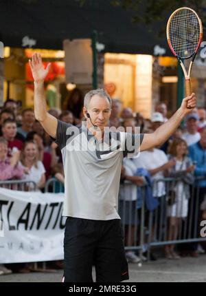Former world number one professional tennis player John McEnroe poses with a custom-made sculpture by artist Jeff Wyman that was presented to him prior to his appearance at 'Tennis on the Ave', a friendly tennis exhibition with Mats Wilander in the middle of Atlantic Avenue.  McEnroe appeared in good spirits as he smiled and threw his arms in the air while playing in front of spectators who had gathered for the event. Delray Beach, FL. 02/18/11. Stock Photo