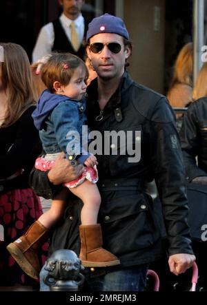 English actor Joseph Fiennes best known for his portrayal of William Shakespeare in 'Shakespeare in Love' was seen at the Grove shopping center carrying his baby girl. The 41 year old actor, who is the youngest brother of actor Ralph Fiennes, wore a blue baseball hat, black jacket, blue jeans, brown shoes and sunglasses. Los Angeles, CA. 22nd March 2012. Stock Photo