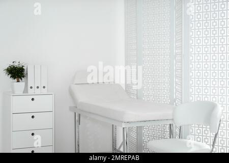 Examination room with modern couch and folding screen in clinic Stock Photo