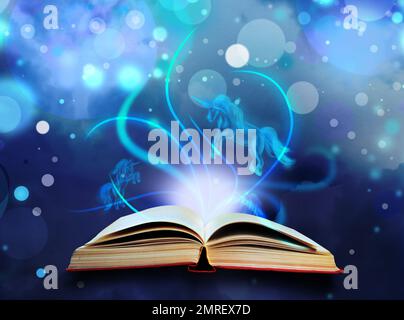 Open book with fairytales and magic lights on blue background. Creative design Stock Photo