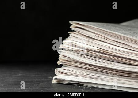 Stack of newspapers on dark stone table, space for text. Journalist's work Stock Photo