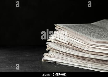 Stack of newspapers on dark stone table, space for text. Journalist's work Stock Photo