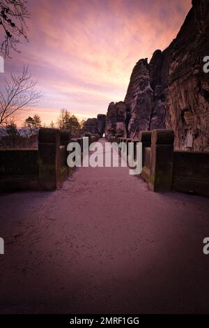 A vertical shot of Bastei bridge in Saxon Switzerland National Park under colorful susnet Stock Photo