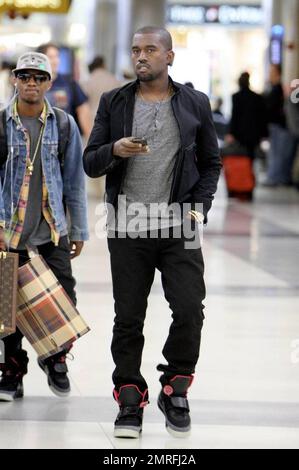 Exclusive!! Kanye West and his posse stroll towards baggage claim at Los Angeles International Airport after arriving on a flight. Kanye is distracted by his cellphone as he strolls, likely checking messages after his flight. Los Angeles, CA. 4/24/09. Stock Photo