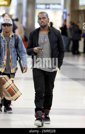 Exclusive!! Kanye West and his posse stroll towards baggage claim at Los Angeles International Airport after arriving on a flight. Kanye is distracted by his cellphone as he strolls, likely checking messages after his flight. Los Angeles, CA. 4/24/09. Stock Photo