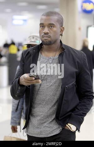 Exclusive!! Kanye West and his posse stroll towards baggage claim at Los Angeles International Airport after arriving on a flight. Kanye is distracted by his cellphone as he strolls, likely checking messages after his flight. Los Angeles, CA. 4/24/09. Stock Photo