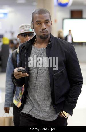 Exclusive!! Kanye West and his posse stroll towards baggage claim at Los Angeles International Airport after arriving on a flight. Kanye is distracted by his cellphone as he strolls, likely checking messages after his flight. Los Angeles, CA. 4/24/09. Stock Photo