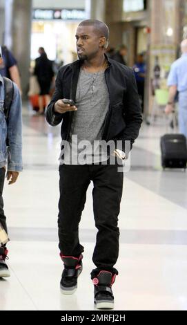 Exclusive!! Kanye West and his posse stroll towards baggage claim at Los Angeles International Airport after arriving on a flight. Kanye is distracted by his cellphone as he strolls, likely checking messages after his flight. Los Angeles, CA. 4/24/09. Stock Photo