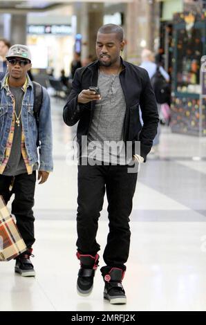 Exclusive!! Kanye West and his posse stroll towards baggage claim at Los Angeles International Airport after arriving on a flight. Kanye is distracted by his cellphone as he strolls, likely checking messages after his flight. Los Angeles, CA. 4/24/09. Stock Photo