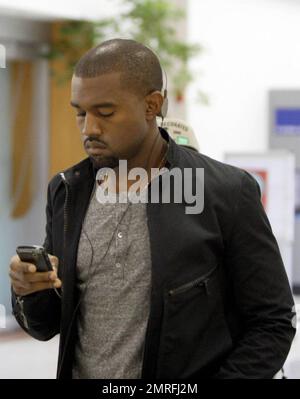 Exclusive!! Kanye West and his posse stroll towards baggage claim at Los Angeles International Airport after arriving on a flight. Kanye is distracted by his cellphone as he strolls, likely checking messages after his flight. Los Angeles, CA. 4/24/09. Stock Photo