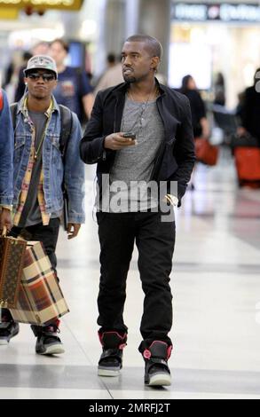 Exclusive!! Kanye West and his posse stroll towards baggage claim at Los Angeles International Airport after arriving on a flight. Kanye is distracted by his cellphone as he strolls, likely checking messages after his flight. Los Angeles, CA. 4/24/09. Stock Photo