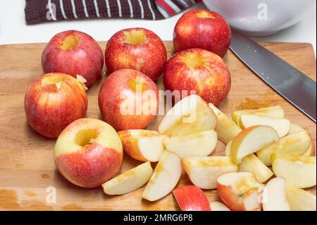 A group of red apples and a knife on a wooden cutting board. Stock Photo