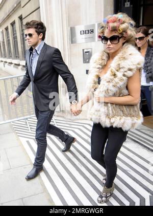 Katie Price and new boyfriend, model Leandro Penna, leave BBC Radio 2. With her hair in curlers, Katie (aka Jordan) wore a fur vest, black leggings and some funky skull-patterned high heels as the two left the building hand-in-hand. Katie, who recently split from husband Alex Reid after less than a year of marriage, has reportedly signed a $1.3 million deal to host a new reality series called 'Make Me a Hunk,' in which she will help to transform 'nerdy' men into hunks. London, UK. 3/22/11. Stock Photo