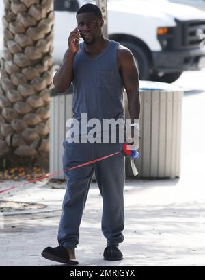 Comedic actor Kevin Hart is spotted walking his dog while conversing on his cell phone and wearing slippers paired with a grey sweat suit outside his Miami hotel. Miami, FL. July 18, 2014. Stock Photo