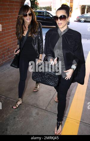 Wearing a black cape over her grey top and carrying a black Louis Vuitton handbag, Kim Kardashian is joined by Pussycat Dolls founder Robin Antin for a day of luxury. The two stopped in at a nail salon for a manicure and did some shopping at Hermes and Chanel. While in the salon, Kim looked shocked during their conversation. Beverly Hills, CA. 12/27/10. Stock Photo