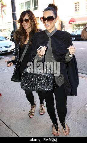 Wearing a black cape over her grey top and carrying a black Louis Vuitton handbag, Kim Kardashian is joined by Pussycat Dolls founder Robin Antin for a day of luxury. The two stopped in at a nail salon for a manicure and did some shopping at Hermes and Chanel. While in the salon, Kim looked shocked during their conversation. Beverly Hills, CA. 12/27/10. Stock Photo