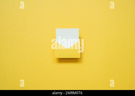 Yellow envelope with white blank card on yellow background. top view, copy space, minimalism Stock Photo