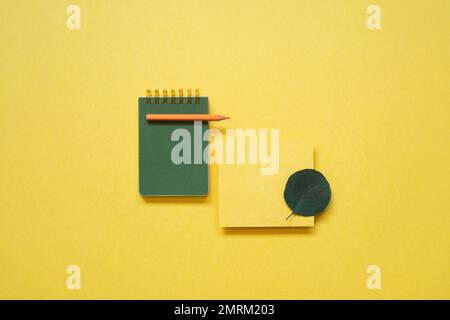 Green notepad, memo paper, color pencil isolated on yellow background. flat lay, top view, copy space Stock Photo