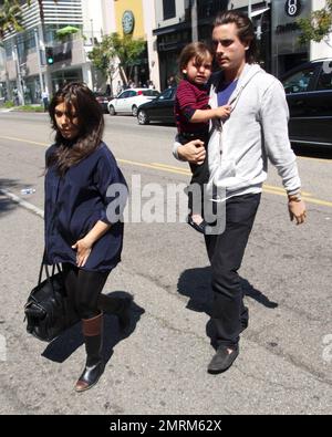 Sporting her new lighter colored hair, pregnant Kourtney Kardashian wears a flowing blue top, black leggings and boots as she leaves a store with boyfriend Scott Disick and son Mason Dash. Kourtney, who is reportedly expecting a baby girl in late spring/early summer, showed her baby bump through her top as Disick carried their son while walking behind. Little Mason looked upset as the three headed to their car. Los Angeles, CA. 21st March 2012. Stock Photo