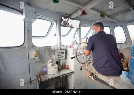 Bangkok,Thailand-December 09 2022: Working on the Phraya River,the operator of a small ferry craft takes passengers to and fro,many times a day,at the Stock Photo