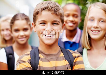 Feeling good about myself, hanging out with schoolmates. Confident young schoolboy posing for the camera with his school friends. Stock Photo