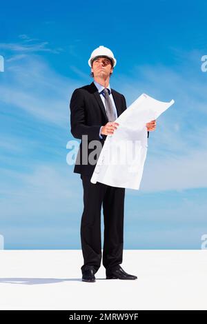 Thoughtful young architect holding a blueprint. Portrait of thoughtful young architect holding a blueprint. Stock Photo
