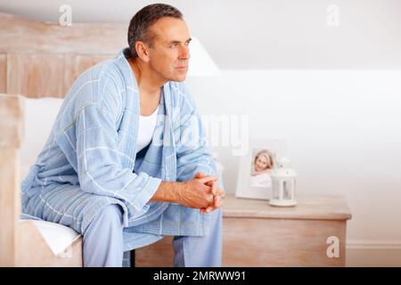 Thoughtful mature man in bathrobe looking away. Portrait of a thoughtful mature man in bathrobe looking away. Stock Photo