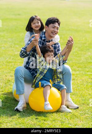 Father and children playing on the grass Stock Photo