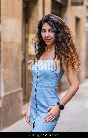 vertical portrait of a beautiful young female model posing for photographer in the street Stock Photo