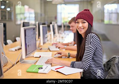 Working towards that A grade. students working on computers in a university library. Stock Photo