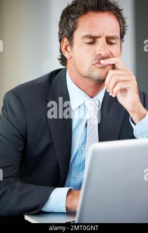 Thoughtful executive using laptop. Thoughtful mature business man working on laptop. Stock Photo