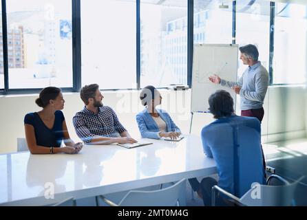 Leading his team with expertise. A businessman doing a presentation using a whiteboard during a boardroom meeting. Stock Photo