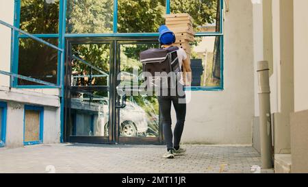 Takeaway employee trying to catch falling pizza packages, being afraid and running from customer at front door after dropping delivery meal. Scared woman with bad delivering service. Tripod shot. Stock Photo