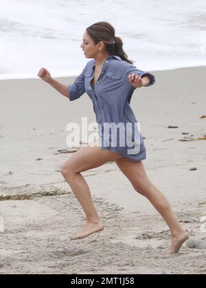 Mila Kunis runs in her bikini and a short blue shirt while filming a