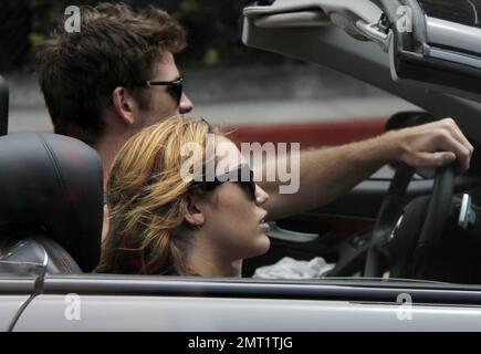 EXCLUSIVE!! Miley Cyrus and boyfriend Australian actor Liam Hemsworth take a ride around town in a convertible sports car driven by Liam before stopping at a center devoted to Meditation.  The lovey-dovey couple spent 30 minutes inside before walking out arm in arm and holding hands.  Miley, wearing jean shorts and a low cut top, tenderly kissed Liam's arm before getting back into the car and zooming off on the day of the Teen Choice awards.  Los Angeles, CA 7th August 2011 Stock Photo